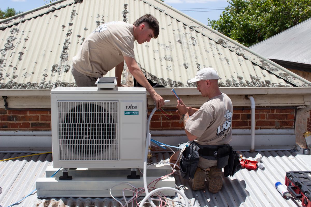 Lamm installers fitting a split system outdoor unit on a roof